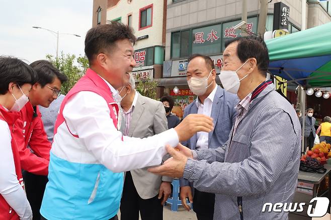 최재구 국민의힘 후보가 덕산시장에서 유권자를 만나 반갑게 인사를 나누고 있다.© 뉴스1 주향 기자