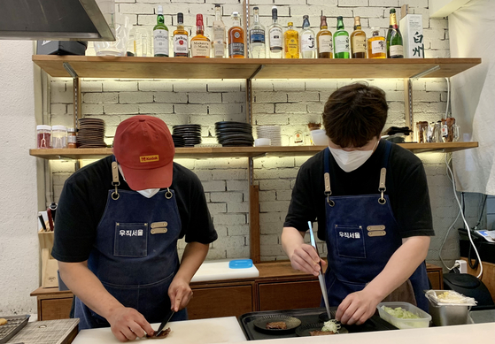 Woo Seung-min, left, cooks with a staff member at Uzik Robatayaki [LEE JIAN]
