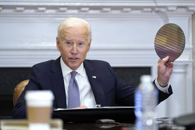 조 바이든 미국 대통령이 지난해 4월 12일(현지 시각) 백악관 루즈벨트룸에서 반도체 업계 대표들과 화상 회의를 진행하는 도중 실리콘 웨이퍼를 꺼내들고 있다. /AP 연합뉴스
