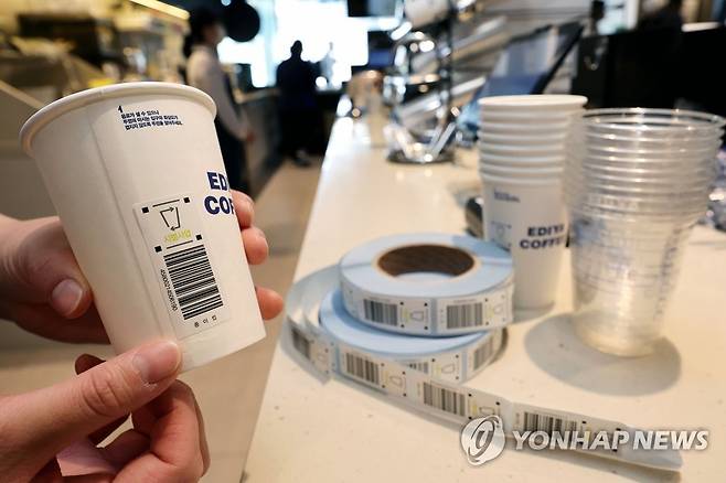 환경부, 일회용 컵 보증금 제도 공개 시연회 (서울=연합뉴스) 김인철 기자 = 일회용 컵 보증금 제도 시행을 앞둔 6일 오후 서울 중구 이디야커피 IBK본점에서 직원이 일회용 컵에 보증금 반환 코드를 부착하고 있다. 2022.5.6 [공동취재] yatoya@yna.co.kr