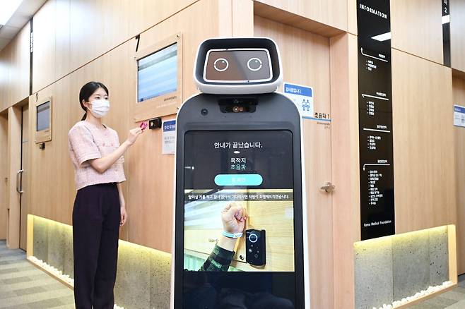 한국의료재단 종합검진센터 직원이 LG 클로이 가이드봇을 활용해 건강검진 안내를 받는 모습을 시연하고 있다. [자료:LG전자]