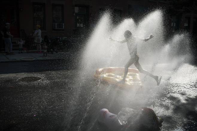 때 이른 폭염이 찾아온 미국 뉴욕에서 21일(현지시간) 한 어린이가 거리의 소화전에서 나오는 물을 맞으며 더위를 식히고 있다. 뉴욕 | AP연합뉴스