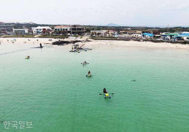 초록빛에 가까운 하고수동해변에서 여행객들이 카약을 즐기고 있다.
