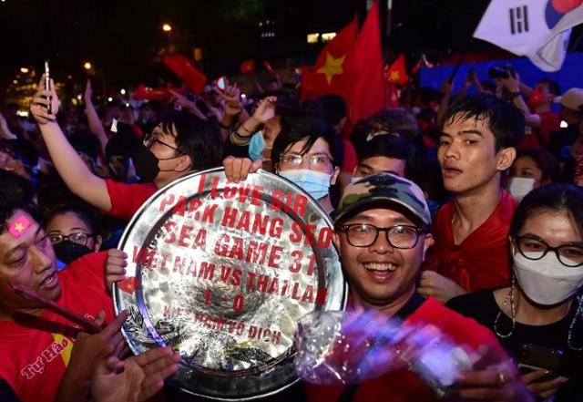 베트남이 제31회 동남아시안게임 남자 축구 종목 금메달을 획득한 22일 하노이 시민들이 "박항서 감독을 사랑한다"는 글이 적힌 패를 들고 환하게 웃고 있다. 베트남넷 캡처