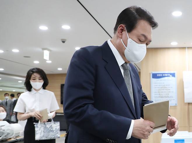 윤석열 대통령과 김건희 여사가 지방선거 사전투표 첫날인 27일 서울 용산구 용산구의회에 마련된 사전투표소에서 투표를 하기 위해 기표소로 들어가고 있다. /뉴시스