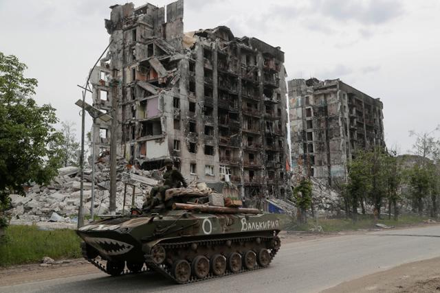 러시아군의 폭격을 받아 폐허로 변한 우크라이나 루한스크주 포파스나에서 26일 러시아군이 탱크를 타고 지나가고 있다. 포파스나=로이터 연합뉴스