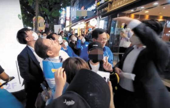 지난 20일 오후 인천 계양구 음식점 앞에서 유세를 위해 이동하던 더불어민주당 이재명 후보가 닭뼈통이 날아온 쪽을 쳐다보고 있다. [유튜브 채널 이재명 캡처]