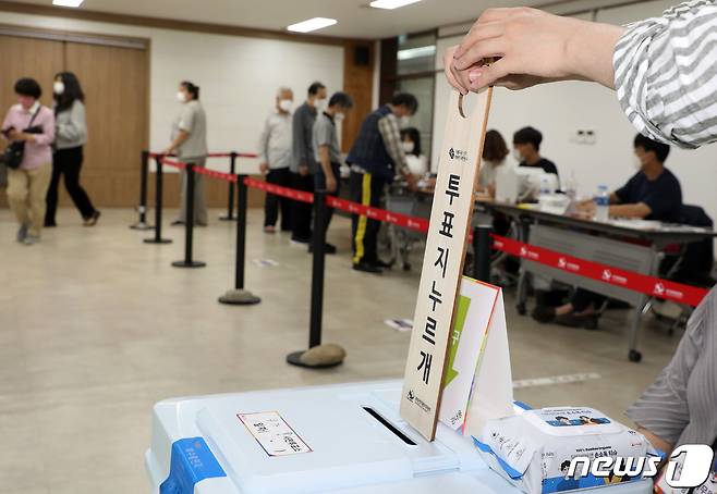 제8회 전국동시지방선거 사전투표 첫날인 27일 오후 대구 달성군 유가읍 행정복지센터에 마련된 사전투표소에서 투표사무원이 투표함에 쌓인 투표용지를 누르기 위해 투표지누르개를 입구에 집어넣고 있다. 2022.5.27/뉴스1 © News1 공정식 기자