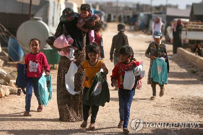 터키 국경 인근의 다나 마을에서 시리아 아이들이 구호품을 받아서 텐트로 향하고 있다.  [AFP=연합뉴스 자료사진. 재판매 및 DB 금지]