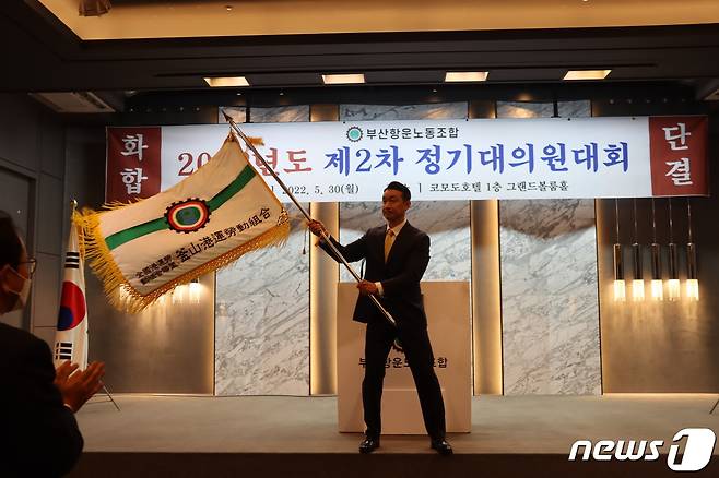 박병근 신임위원장이 30일 부산 코모도호텔에서 열린 '2022년도 제2차 정기대의원대회'에서 깃발을 흔들고 있다. (부산항운노조 제공)© 뉴스1