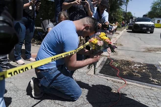[유밸디=AP/뉴시스] 25일(현지시간) 미 텍사스주 유밸디에서 한 남성이 롭 초등학교 총기 난사 희생자들을 추모하는 꽃을 들고 기도하고 있다. 24일 총격범 살바도르 라모스(18)의 총격으로 이 학교 학생 19명과 교사 2명이 숨졌고 라모스는 사살됐다. 2022.05.26.