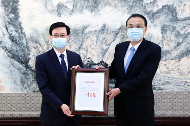 리커창 중국 국무원 총리(오른쪽)가 30일 중국 베이징을 방문한 존 리 신임 홍콩 행정장관 당선인을 만나 임명장을 수여하고 있다. 베이징=신화 연합뉴스