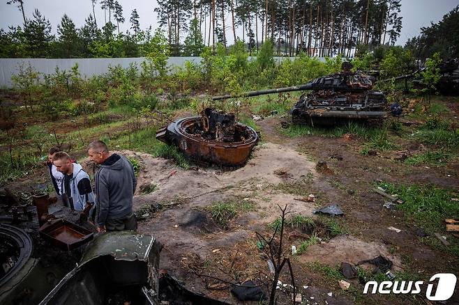 지난달 31일(현지시간) 우크라이나 수도 키이우 인근에서 주민들이 파괴된 러시아 군 탱크를 살펴 보고 있다. © AFP=뉴스1