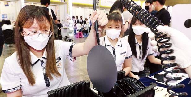 ‘2022 대한민국 고졸 인재 채용엑스포’에 마련된 충북반도체고 부스에서 학생들이 반도체의 토대가 되는 웨이퍼를 살펴보고 있다.  /김범준 기자