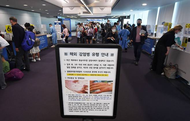 지난달 27일 인천국제공항 제1터미널 입국장에서 해외 입국자들이 검역을 받기 위해 대기하고 있다. 입국자들 앞에 원숭이두창 관련 안내문이 세워져 있다. /뉴스1