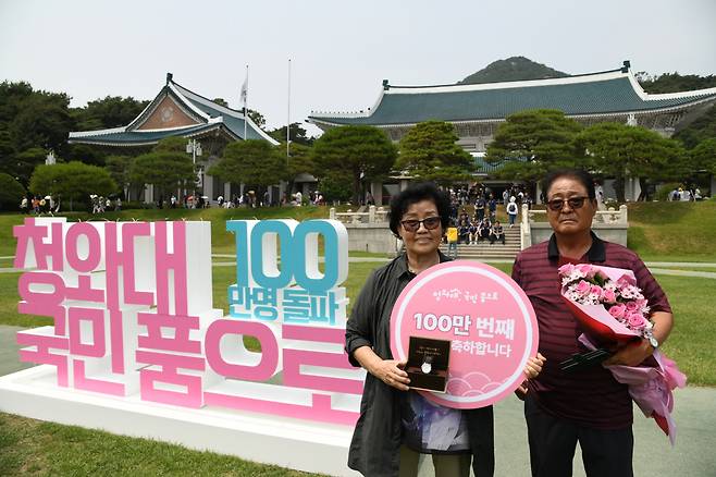 22일 오후 청와대 대정원에서 열린 '100만 번째 청와대 관람객' 기념행사에서 100만 번째 관람객으로 선정된 김영순 씨가 기념품으로 받은 대통령 기념 시계를 들고 기념촬영을 하고 있다. [대통령실 제공]