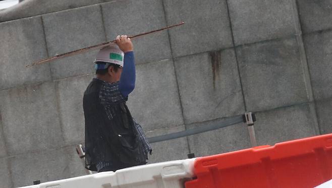 23일 오후 서울 종로구 광화문광장 공사현장에서 한 노동자가 나무 합판으로 비를 피하고 있다. 백소아 기자