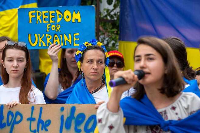 People hold placards as they rally in support of the Ukraine, following Russia's invasion of its neighbour in February 2022, in Brussels as EU-Western Balkans leaders' meet in the city on June 23, 2022. (AFP)