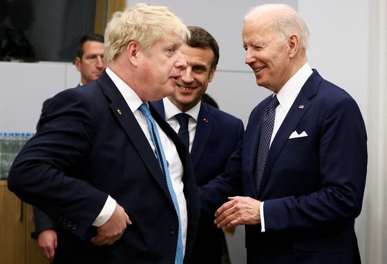 지난 3월 24일 보리스 존슨 영국 총리가 조 바이든 미국 대통령과 벨기에 브뤼셀에서 열린 주요7개국(G7) 회의를 앞두고 대화를 나누고 있다. 가운데에서 에마뉘엘 마크롱 프랑스 대통령이 웃으며 두 정상을 바라보고 있다. [로이터=연합뉴스]