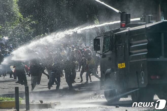 22일(현지시간) 에콰도르 키토에서 진압 경찰이 기름값 인상에 항의하는 시위대를 향해 물대포를 쏘고 있다. © AFP=뉴스1
