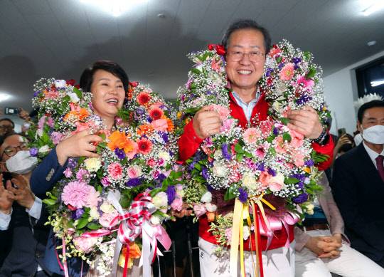 지난 6월1일 오후 홍준표(오른쪽) 당시 국민의힘 대구광역시장 후보가 개표 중 당선이 확실시되자 자신의 대구 중구 선거사무소에서 부인 이순삼씨와 함께 당선 축하 꽃다발을 받은 채 기뻐하고 있다.<연합뉴스>