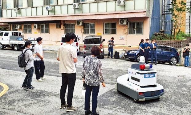 < 사람 없이 못 다니는 방범 로봇 > 지난 16일 서울 신림동 해태어린이공원 인근 골목길에서 관악구, 관악경찰서 등 관계자와 시민들이 지켜보는 가운데 자율주행 방범 로봇 ‘골리’가 모니터링 요원(왼쪽 세 번째)을 대동한 채 순찰을 하고 있다.  박한신 기자