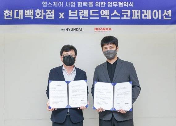 브랜드엑스코퍼레이션 박희종 부대표(오른쪽)와 현대백화점 미래사업부 박채훈 상무가 28일 현대백화점 본사에서 헬스케어 콘텐츠 강화를 위한 업무협약 체결 후 기념촬영을 하고 있다.