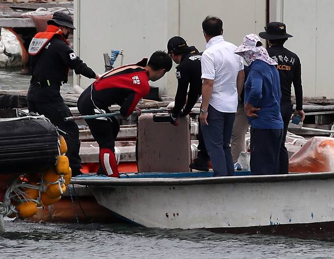 28일 오후 전남 완도군 신지면 송곡선착장 방파제로부터 80m 지점 가두리 양식장 아래에서 실종된 조유나(10) 양 가족의 차량으로 추정되는 아우디 승용차가 발견됐다. 경찰이 수중에 있는 차량 내에서 케리어를 건져 올리고 있다. [연합]