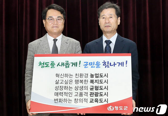 김하수 청도군수(왼쪽)이 박진우 청도군수직 인수위원장으로부터 시정 슬로건과 5대 군정방침을 전달받고 있다. (청도군 제공)2022.6.30/© 뉴스1
