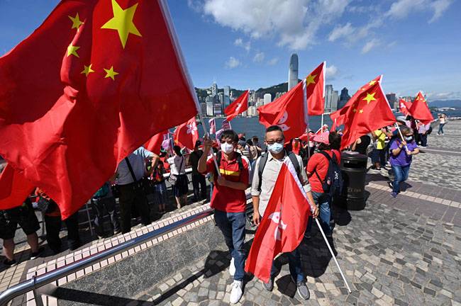 홍콩 반환 25주년을 앞둔 28일 홍콩 빅토리아항에서 시민들이 중국 오성홍기와 홍콩 국기를 들고 있다. 영국 식민지였던 홍콩은 지난 1997년 7월 1일 중국에 반환됐다. 연합뉴스·AFP