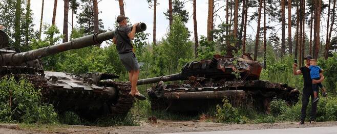 우크라이나 드미트리우카 지역 고속도로에 러시아군이 이번 전쟁에 사용한 장갑차와 탱크 세워져 있다. 자녀와 함께 현장을 찾은 우크라이나 시민들이 기념사진을 찍고 있다. 드미트리우카/김혜윤 기자 unique@hani.co.kr