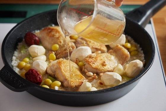 밥을 짓기 전에 팬에 닭 다리를 구운 후 올려주면 풍미가 더 좋다. 사진 맛있는책방