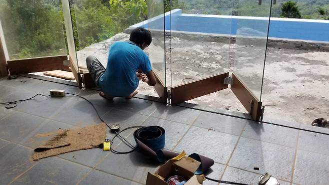 목재가 휘어서 제대로 움직이지 않는 접이식 창을 수리 중이다.