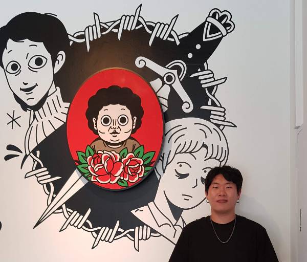 웹툰 ‘악몽의 형상’을 연재하고 있는 김용키 작가가 전작인 ‘타인은 지옥이다’의 대형 일러스트 앞에서 포즈를 취했다. 네이버웹툰 제공