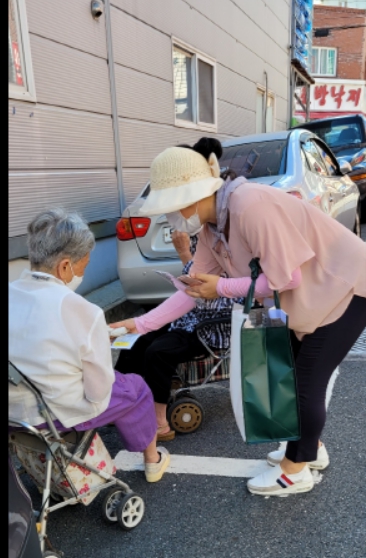 부산 예향교회 김봉정(오른쪽) 사모가 지난달 부상 동래구 교회 인근의 거리에서 한 할머니에게 전도지와 용품을 전달하고 있다.