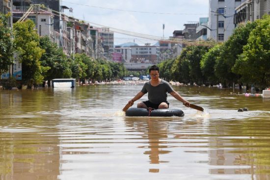 지난 6월 중국 광둥성에 폭우가 내린 뒤 물에 잠긴 도로를 한 남성이 노를 저으며 건너고 있다 [이미지출처=로이터연합뉴스]