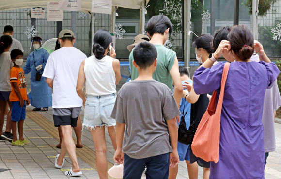 신규 확진 2만명 육박… 다시 북적이는 선별진료소 - 6일 서울 서초구보건소 선별진료소에서 시민들이 코로나19 검사를 받기 위해 줄을 서 있다. 이날 0시 기준 신규 확진자가 1만 9371명 발생하면서 이틀 연속 2만명에 육박하는 수치를 보였다. 또 다른 오미크론 변이인 BA.5가 확산하는 데다 백신 효력이 떨어지면서 확진자 증가세를 보이는 것으로 분석된다. 연합뉴스