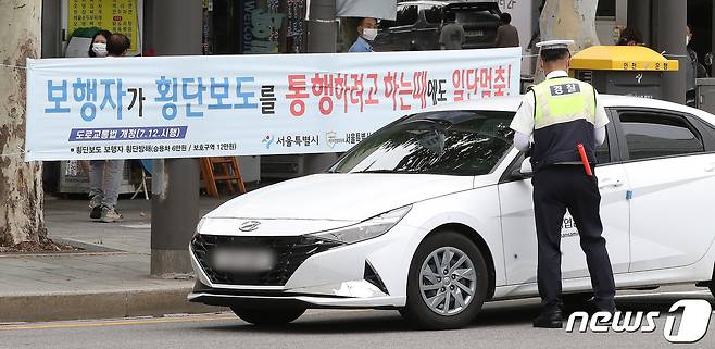 횡단보도 앞 일시정지 등 보행자 보호 의무를 강화한 도로교통법 개정안 시행 첫날인 12일 서울 종로구 이화사거리에서 경찰이 계도에 나서고 있다.  © News1 임세영 기자