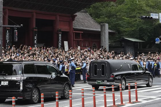 12일 오후 아베 신조 전 총리의 운구차가 조조지를 출발하자 거리의 시민들이 휴대폰 카메라로 촬영을 하고 있다. [AP=연합뉴스]