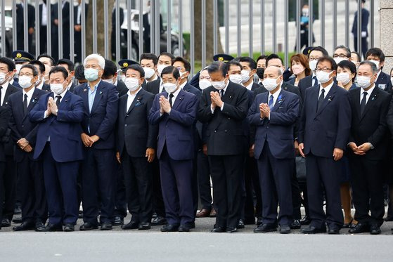 12일 오후 일본 도쿄 국회의사당 앞에서 국회의원들이 아베 신조 전 총리의 운구차를 향해 손을 모으고 서 있다. [로이터=연합뉴스]