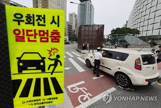 개정 도로교통법 시행 '우회전 시 일단 멈춤' (서울=연합뉴스) 임헌정 기자 = '횡단보도 보행자 보호'를 골자로 하는 개정 도로교통법 시행 첫날인 12일 서울 송파구 잠실역 교차로에서 송파경찰서 경찰관들이 계도 활동을 하고 있다. 2022.7.12 kane@yna.co.kr