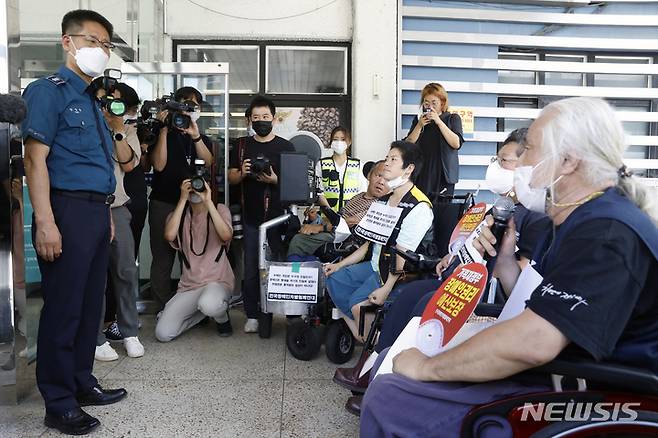 [서울=뉴시스] 고승민 기자 = 전국장애인차별철폐연대(전장연) 회원들이 14일 서울 혜화경찰서에서 전장연 활동가들의 지하철 시위 조사에 대해 엘리베이터 설치 후 자진출석 하겠다는 의사를 밝히며 관계자와 대화하고 있다. 2022.07.14. kkssmm99@newsis.com