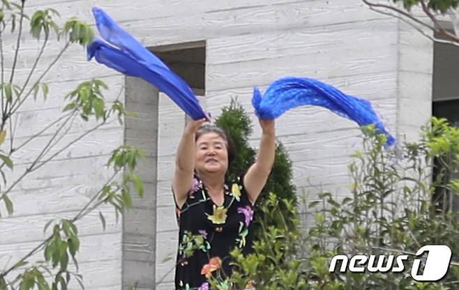 김정숙 여사가 17일 경남 양산 하북면 평산마을 문재인 전 대통령 사저앞에서 열린 문 전 대통령 규탄 집회와 평산마을 일상회복 기원집회가 동시에 진행되는 가운데 일상회복 기원집회자들을 향해 파란수건을 흔들고 있다. 2022.7.17/뉴스1 © News1 김영훈 기자