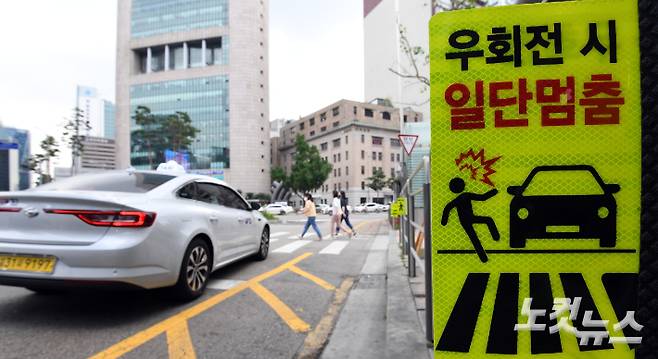 개정 도로교통법 시행을 하루 앞둔 지난 11일 서울시내 한 횡단보도 앞에 관련 현수막이 보행자 안전을 위한 일단 멈춤 표시가 설치된 모습. 황진환 기자