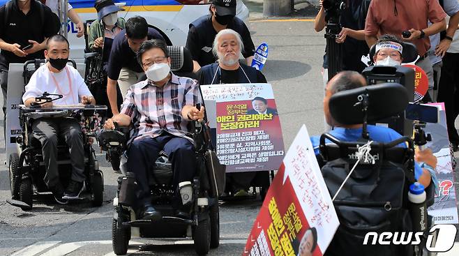 박경석 전국장애인차별철폐연대(전장연) 대표와 회원들이 19일 오전 서울 용산경찰서에 출석하고 있다. 이날 전장연은 장애인 이동권 보장을 요구하며 출퇴근길 지하철 시위를 한 것과 관련해 조사를 받기 위해 용산경찰서에 출석했다가 청사에 장애인 등 교통약자를 위한 승강기가 설치되지 않았다며 조사를 거부하고 돌아갔다. 2022.7.19/뉴스1 © News1 구윤성 기자