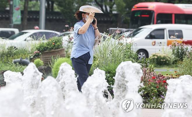 한 시민이 서울 중구 서울광장 분수대에서 부채로 햇빛을 가리고 있다. [연합뉴스 자료사진]