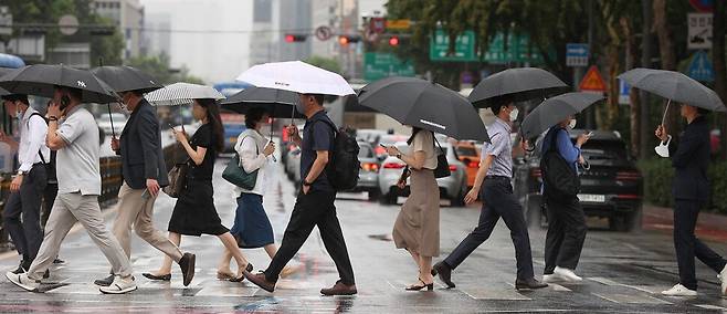 전국 곳곳 비 소식이 예보된 21일 오전 서울 종로구 광화문네거리에서 시민들이 우산을 쓴 채 이동하고 있다. 연합뉴스