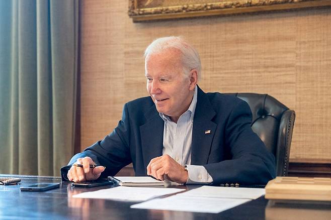 U.S. President Joe Biden, who tested positive for COVID-19 while experiencing mild symptoms, sits at his desk in the White House residence in this handout photo obtained from President Biden's Twitter account on July 21, 2022.  /로이터=뉴스1