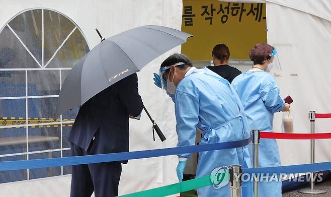 비 맞으며 코로나검사 안내하는 의료진 (서울=연합뉴스) 김인철 기자 = 21일 오전 서울 강남구보건소 코로나19 선별진료소에서 의료진이 검사를 받으려는 시민들을 안내하고 있다. 2022.7.21 yatoya@yna.co.kr