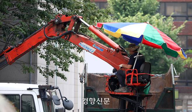 서울 시내 한 건설현장에서 한 노동자가 파라솔을 치고 크레인 위에서 작업을 하고 있다. 권도현 기자